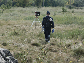 Ein Mitarbeiter mit mobilem ODL-Messgerät geht in Richtung eines In-situ-Gammaspektrometers  (Bild anzeigen)